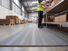 Grey ribbed PVC foam anti-fatigue matting laid along a packing bench in a warehouse despatch area