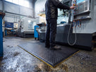 14mm black checker-plate anti-fatigue foam mat in front of a CNC machine in an engineering workshop