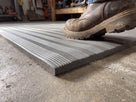 Close-up of the fine ribbed surface and chamfered edge of 9mm grey PVC foam matting under a work boot