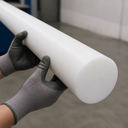 Bright white UHMWPE rod supported by grey gloved hands, smooth rounded end face in the foreground