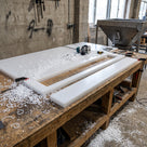 Natural white UHMWPE sheet on a fabrication bench with a routed liner strip cut from it, router and swarf alongside