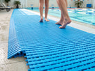 Blue EVA interlocking tiles on a swimming pool surround with bare feet walking across them