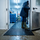 Black open mesh PVC matting running through a walk-in chilled food store doorway, rated to minus 23 degrees C