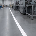 White floor marking tape line running along a factory floor beside a production line