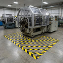 Yellow and black diagonal striped floor marking tape hatching a hazard zone on the floor around a guarded machine